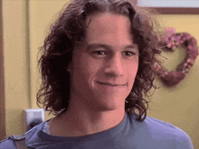 a man with long curly hair is smiling and looking at the camera