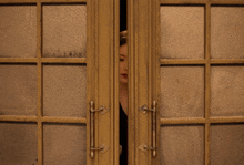 a woman in a black suit is peeking out of a door