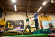 a man is helping another man do a trick on a box that says chester 's