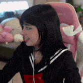 a woman wearing headphones sits in a pink chair that says ' g ' on it