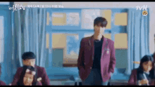 a man in a red jacket is standing in a classroom with a group of students .