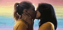 two women are kissing in front of a colorful background .