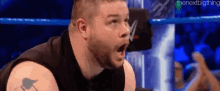 a wrestler is making a funny face while sitting in a wrestling ring .