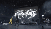 a group of people on stage with a large screen behind them that says ' ghostemane '
