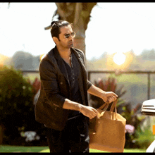 a man wearing sunglasses holds a brown bag