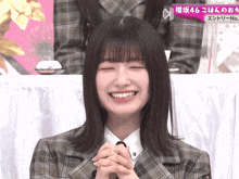 a girl in a plaid jacket smiles with her eyes closed in front of a sign that says 46