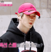 a young man wearing a red hat and a black hoodie is sticking his tongue out .