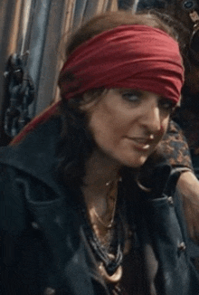 a woman wearing a red headband and a black jacket is looking at the camera .