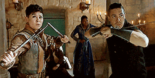 a man and a woman are holding swords in a room with candles