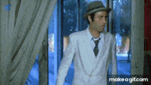 a man in a white suit and hat is standing in front of a door .