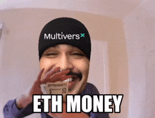 a man wearing a hat that says multivers holds a stack of money in his hand