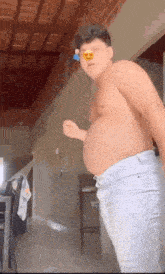 a shirtless man with a very large belly is standing in a living room .
