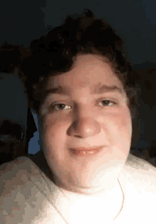 a young man with a necklace around his neck is smiling