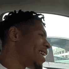 a man with dreadlocks is smiling while sitting in the back seat of a car