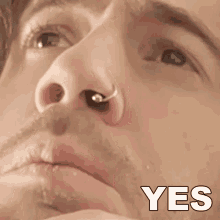 a close up of a man 's face with a nose ring and the word yes in white letters