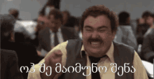 a man with a mustache is making a funny face in front of a group of people with foreign writing on the screen