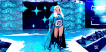 a woman in a wrestling outfit is walking down a stage with a wwe logo on the wall behind her