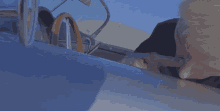 a man is looking at a tiny figure laying on the hood of a car