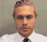 a man in a white shirt and tie is making a funny face .