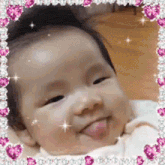 a baby is sticking out his tongue in a picture frame with hearts .