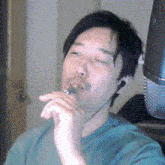 a man in a green shirt is smoking a cigarette