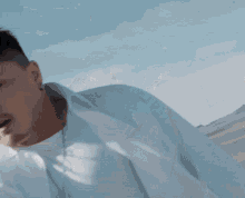 a man in a white shirt is holding a white cloth over his shoulders