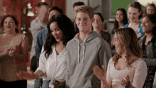 a group of people are clapping and smiling while standing in a line