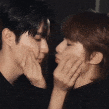 a man and woman are touching each other 's faces with their hands