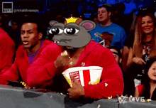 a man in a red hoodie is eating popcorn with a cartoon mouse on his head