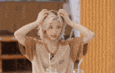 a woman with blonde hair is scratching her head with her hands .