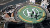 a group of soldiers are running on a helipad with a letter h on it