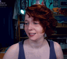 a woman with red hair is smiling in front of a sign that says ' gifted x1 '