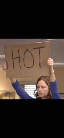 a woman is holding up a cardboard sign with the word hot written on it