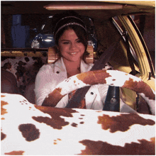 a woman sitting in a car with a cow print seat