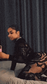 a woman laying on a bed taking a picture of herself in the mirror