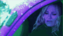 a woman is sitting in a car with a purple stripe on the windshield