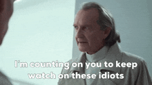 a man in a trench coat says " i 'm counting on you to keep watch on these idiots " .