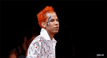 a man with red hair is singing into a microphone with a tattoo on his face