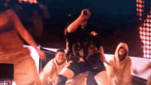 a group of people are dancing in front of a screen that says " hella "