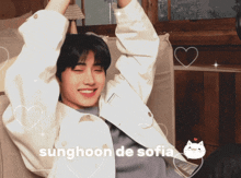 a young man is sitting on a couch with his arms outstretched and the words sunghoon de sofia above him