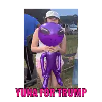 a woman holding a purple inflatable alien with yuna for trump written in pink
