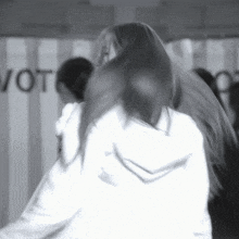a woman with long hair is standing in front of a wall that says vote
