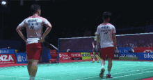two badminton players standing on a court with one wearing a shirt that says indonesia
