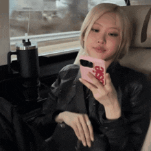 a woman is sitting in a car looking at her phone with a case that says ' supreme ' on it