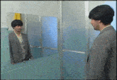 a man in a suit stands in front of a mirror