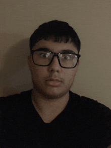 a man wearing glasses and a black shirt is looking at the camera