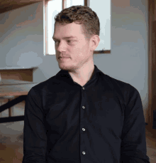 a man in a black shirt is looking to his left