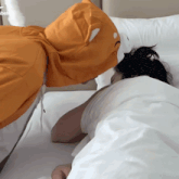 a man in an orange cat hoodie kisses a woman in bed