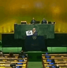 a man is sitting at a podium with a cat on his laptop .