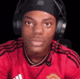 a man wearing headphones and a red shirt is sitting in a chair .